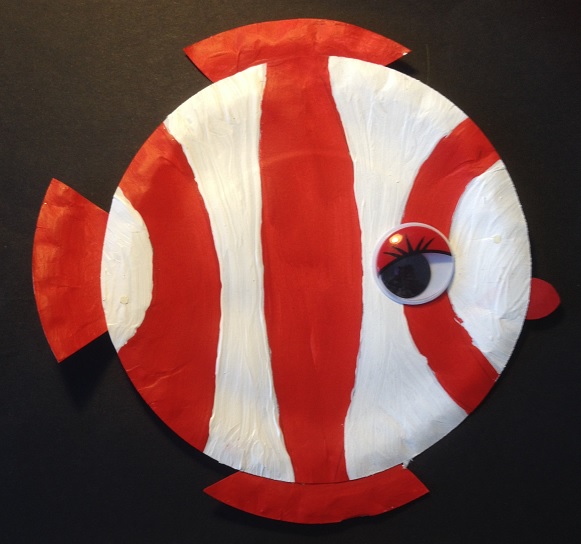 En röd- och vitrandig fisk målad på en papptallrik